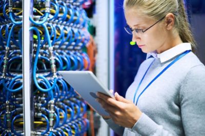 IT worker holding tablet reviewing mainframe operations, Managed Mainframe Services | DXC Technology